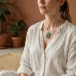 Femme portant un collier amazonite sur la peau au niveau de la clavicule dans un espace de méditation minimaliste