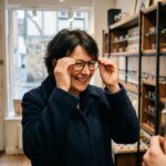 Femme souriante essayant des lunettes dans une boutique optique