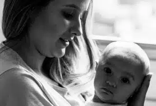 woman in white shirt carrying baby in grayscale photography