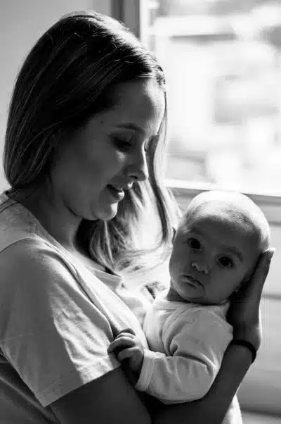 woman in white shirt carrying baby in grayscale photography