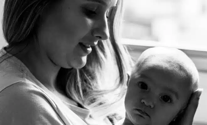 woman in white shirt carrying baby in grayscale photography